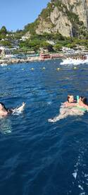 A lively group enjoys swimming in the clear waters off the coast of Capri, creating unforgettable memories in a stunning seaside setting.