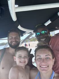 A joyful family poses for a selfie on a boat, capturing a fun day at the beach with smiles all around.