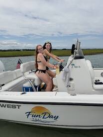 Two friends enjoy a sunny day on the water, taking the helm of a Fun Day boat — perfect for summer adventures and memorable outings.