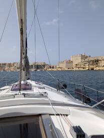 A stunning view from the deck of a sailboat, showcasing the vessel's structure as it navigates near a historic coastal fortification.