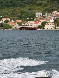 A picturesque view of a yacht docked along a scenic waterfront, surrounded by charming homes and lush greenery, perfect for exploring coastal destinations.
