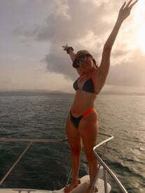 A joyful woman poses on the deck of a boat, celebrating under the clouds — a perfect moment for fun and adventure on the water.