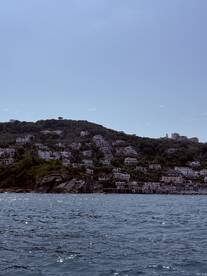 A picturesque view of a coastal town nestled on a hillside, showcasing beautiful architecture against a serene water backdrop — perfect for exploring scenic destinations by boat.