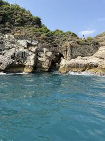 A scenic view of a rocky coastline with lush greenery, featuring a person exploring the area — a perfect backdrop for coastal adventures.
