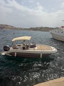 A sleek speedboat named Calionboats is docked in clear waters, showcasing its elegant design against a scenic coastal backdrop.