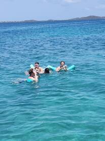 A lively group enjoys swimming in crystal-clear waters, showcasing the fun and excitement of water activities during their boating adventure.