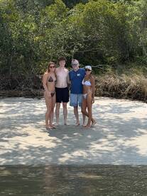 A cheerful group poses on the beach, enjoying a sunny day by the water — perfect for memorable beach outings and celebrations.