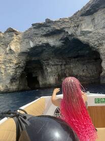 A child enjoys the view from a boat while exploring a stunning cave along the coastline, capturing the essence of adventure on the water.