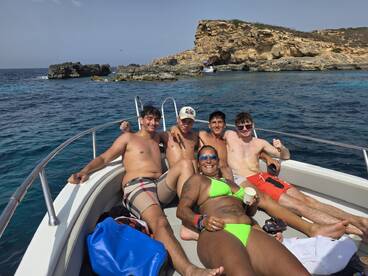 A lively group of friends enjoys a sunny day on the boat, celebrating and relaxing in the beautiful waters — perfect for summer adventures.