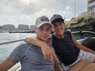 Two friends enjoy a fun moment on a boat, showcasing camaraderie and smiles against a scenic backdrop.