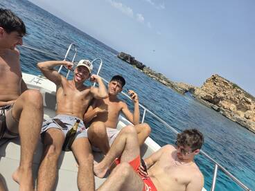 A lively group of friends enjoys a fun day on the boat, showcasing camaraderie and celebration against a stunning coastal backdrop.