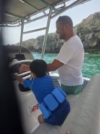 A joyful moment as a father and son bond while navigating a boat, showcasing family fun on the water.