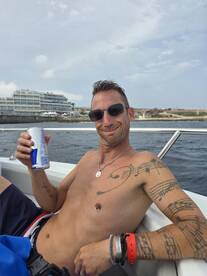 A man enjoys a refreshing drink while relaxing on a boat, showcasing a laid-back atmosphere perfect for summer outings on the water.