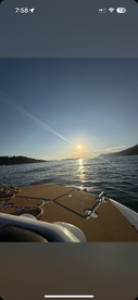 A serene sunset view from the deck of a boat, showcasing the tranquil waters and distant hills — perfect for peaceful evening cruises.