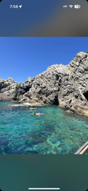 Snorkelers explore the vibrant underwater world near a rocky coastline, showcasing the beauty of clear waters and marine life — a perfect adventure for water enthusiasts.