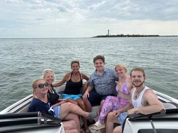 A cheerful group of friends enjoys a day on the water, capturing memories aboard their boat with a scenic backdrop.