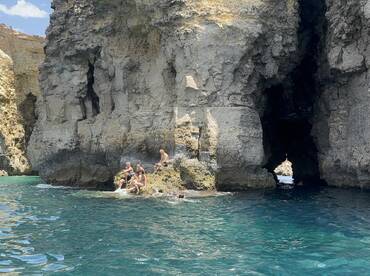A group of friends enjoys a sunny day by the stunning rock formations, creating a perfect backdrop for swimming and relaxation in crystal-clear waters.