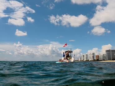 A group enjoys a day on the water, preparing for snorkeling activities near the shore, with a beautiful backdrop of clouds and buildings.