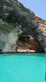 Swimmers enjoy the stunning turquoise waters near a natural cave, creating a picturesque backdrop for a memorable boating adventure.
