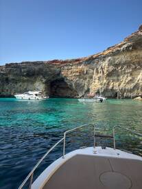 A stunning view of boats anchored near a picturesque cave, surrounded by crystal-clear turquoise waters — a perfect spot for exploration and relaxation.