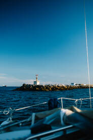 A picturesque view of a lighthouse at the harbor, captured from a boat, showcasing the serene beauty of coastal navigation.