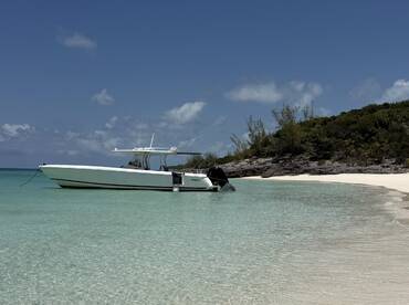 A sleek speedboat anchored in crystal-clear turquoise waters, showcasing the perfect spot for a day of relaxation on the beach.