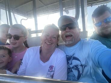 A joyful family captures a selfie aboard a boat, showcasing smiles and togetherness during their aquatic adventure.