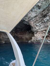 A scenic view from a boat approaching a stunning cave, showcasing the vibrant blue water and rocky formations — perfect for adventure seekers exploring coastal wonders.