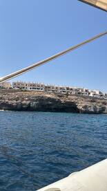 A scenic view of a rocky coastline with buildings perched above the water, captured from a boat — perfect for showcasing beautiful destinations while cruising.