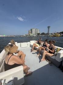 A lively group enjoys drinks aboard a pontoon boat, soaking up the sun and good vibes on the water — perfect for a fun day out with friends.