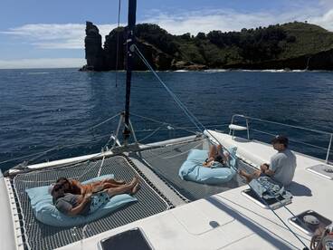 A couple relaxes on a catamaran, enjoying the serene ocean views and beautiful scenery — a perfect getaway for leisure and tranquility.