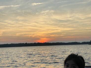 A beautiful sunset over the water with a child in the foreground, capturing a serene moment perfect for family outings on the boat.