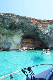 A scenic view of boats exploring a stunning cave along the coastline, with vibrant turquoise waters creating a perfect backdrop for a memorable boating adventure.