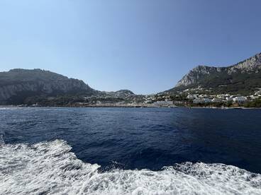 A stunning view of the coastline and hills of Capri, showcasing the beautiful landscape and crystal-clear waters — perfect for island-hopping adventures.