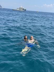 A couple enjoys a refreshing swim in the ocean with a boat in the background, capturing the essence of a perfect day on the water.
