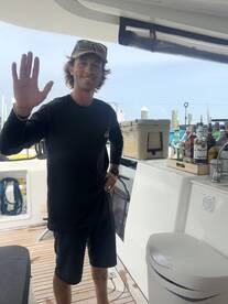 A friendly crew member greets guests aboard the boat, showcasing the interior space with a well-stocked bar area — perfect for entertaining on the water.