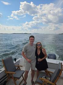 A cheerful couple enjoys drinks on a boat with a stunning city skyline in the background, perfect for memorable outings and celebrations on the water.