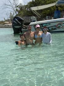 A joyful family enjoys a day in the shallow waters, creating unforgettable memories with their boat in the background — perfect for summer adventures.