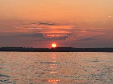 A stunning sunset over calm waters, creating a picturesque backdrop for evening boat outings.