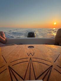 A serene sunset view from a boat, showcasing the calm ocean and relaxed passengers enjoying the tranquil atmosphere.