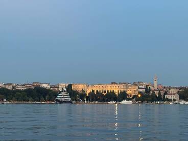 A picturesque view of a harbor at dusk, featuring a luxurious yacht and the illuminated architecture of the city in the background, perfect for showcasing scenic boating destinations.