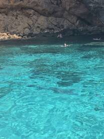 A vibrant scene of swimmers enjoying the crystal-clear waters near a rocky coastline, perfect for a day of adventure and relaxation.