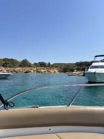 A scenic view from the bow of a boat, showcasing the tranquil waters and nearby vessels in a picturesque harbor setting.