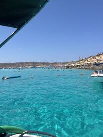 A vibrant scene at a popular beach with clear turquoise waters, showcasing people enjoying swimming and sunbathing — a perfect destination for summer fun.