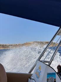 A thrilling moment on the water as the boat speeds through waves, creating splashes against a scenic backdrop — perfect for adventure seekers enjoying their day out at sea.