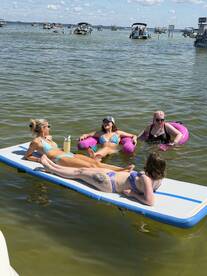 A fun group of friends relaxes on a floating mat in the water, enjoying a sunny day filled with laughter and good vibes — perfect for summer outings.