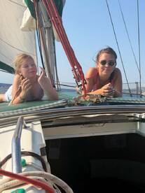 Two young girls enjoy a sunny day sailing, relaxing on the deck of a boat — a perfect moment of fun and adventure on the water.