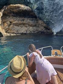 A child and an adult lean over the side of a boat, captivated by the stunning rock formations and clear waters, showcasing a memorable family adventure on the water.