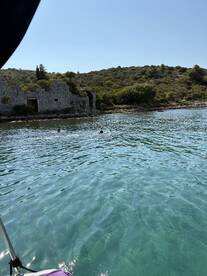Two swimmers enjoy the crystal-clear waters near ancient ruins, creating a picturesque scene perfect for summer adventures.