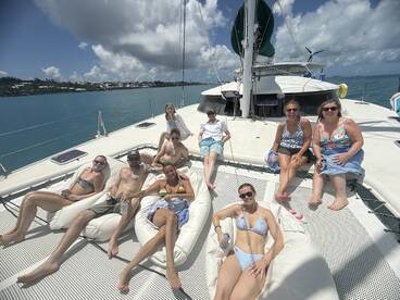 A lively group enjoys a sun-soaked day on a catamaran, lounging on bean bags and sipping drinks — perfect for a fun-filled boat party.